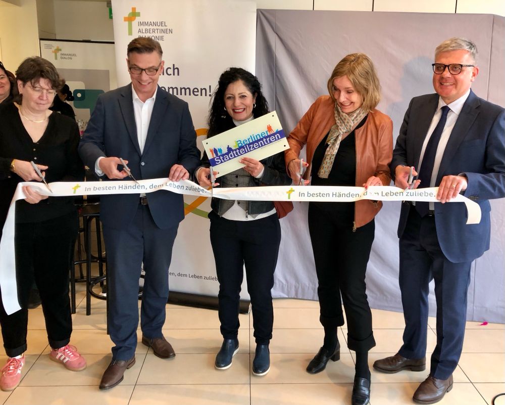(v.l.n.r.) Pfarrerin Dagmar Wegner, Konzerngeschäftsführer Immanuel Albertinen Diakonie Andreas Mende, Senatorin für Arbeit, Soziales, Gleichstellung, Integration, Vielfalt und Antidiskriminierung Cansel Kiziltepe, MdA Catherina Pieroth-Manelli und CEO Immanuel Albertinen Diakonie Matthias Scheller beim Durchschneiden des Eröffnungsbands. Die Senatorin hält das Schild mit dem Text-Logo "Berliner Stadteilzentren".