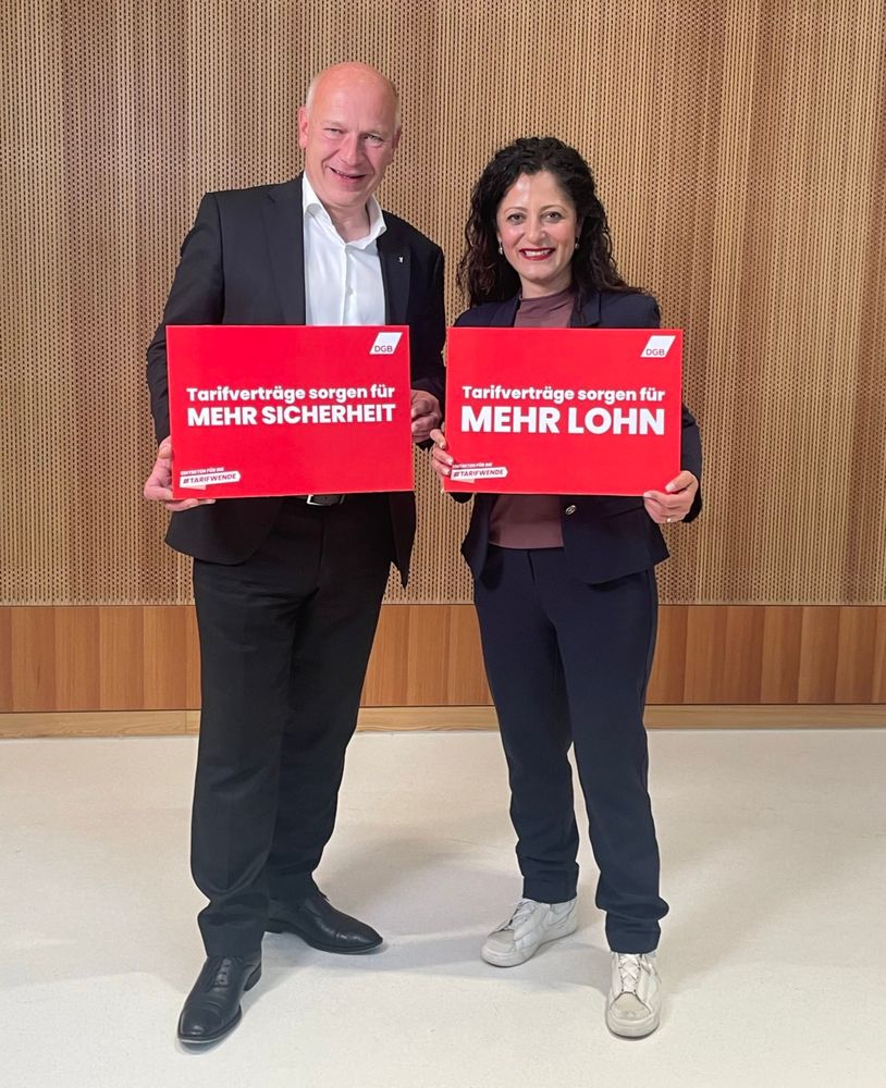 Senatorin für Arbeit, Soziales, Gleichstellung, Integration, Vielfalt und Antidiskriminierung Cansel Kiziltepe und Regierender Bürgermeister Kai Wegner stehen und halten jeweils ein Schild in den Händen. Auf dem Schild von Kai Wegner steht: "DGB. Tarifverträge sorgen für MEHR SICHERHEIT". Auf dem Schild von Cansel Kiziltepe steht: "DGB. Tarifverträge sorgen für MEHR LOHN".