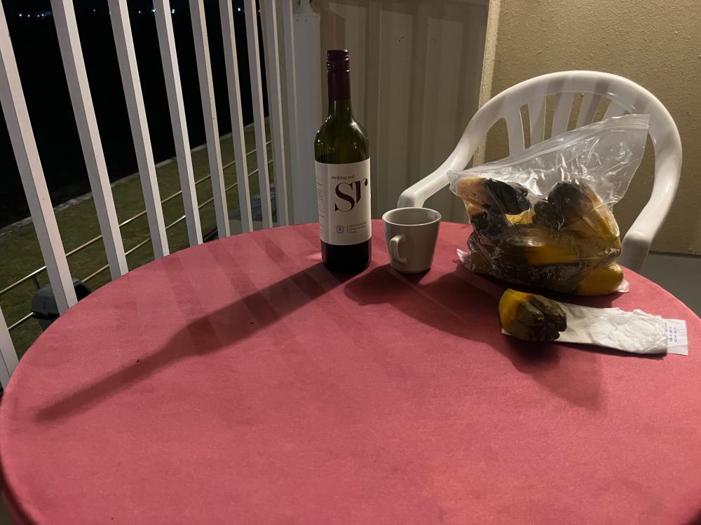 Stilleben with four-dollar bag of bōb lobes from the bōb and breadfruit ladies at the market minus about five lobes, like I said; image from a lagoonside balcony also includes an eight buck bottle of Oz plonk and a hotel coffee cup from which to drink said plonk. Lighting: terrible