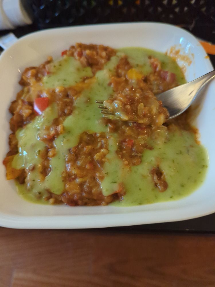 Bowl of rice, lentils, and tomatoes drizzled with guacamole salsa.

It is basically premixed burrito filling.