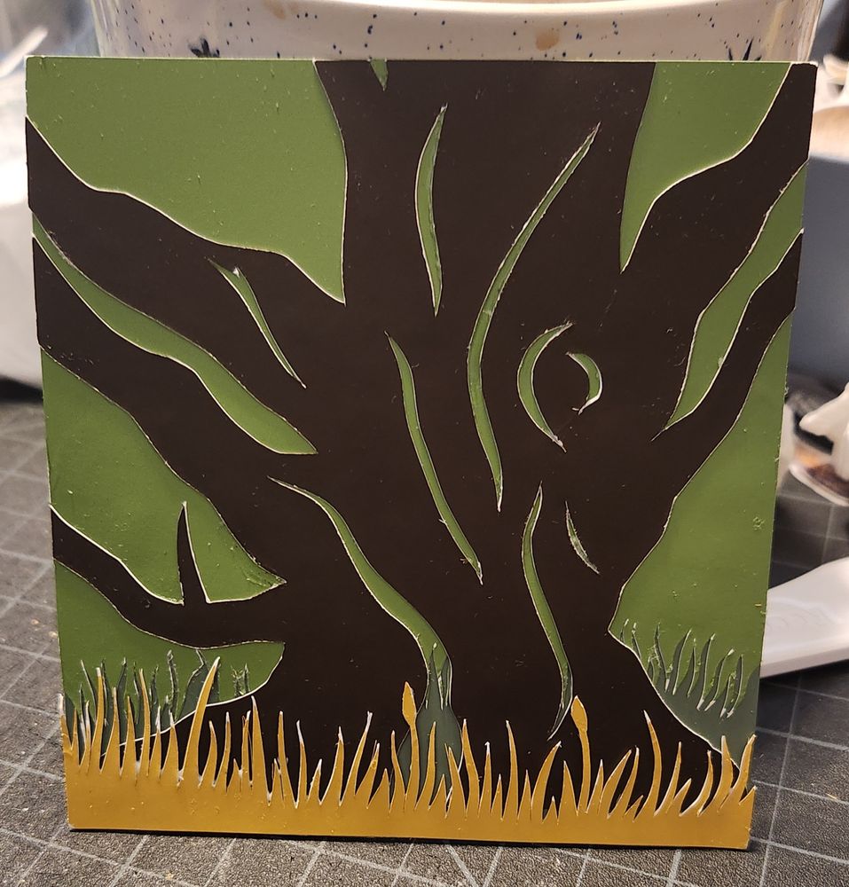Golden grass over a dark brown gnarled tree branching out on each side with a two toned green grassy background.