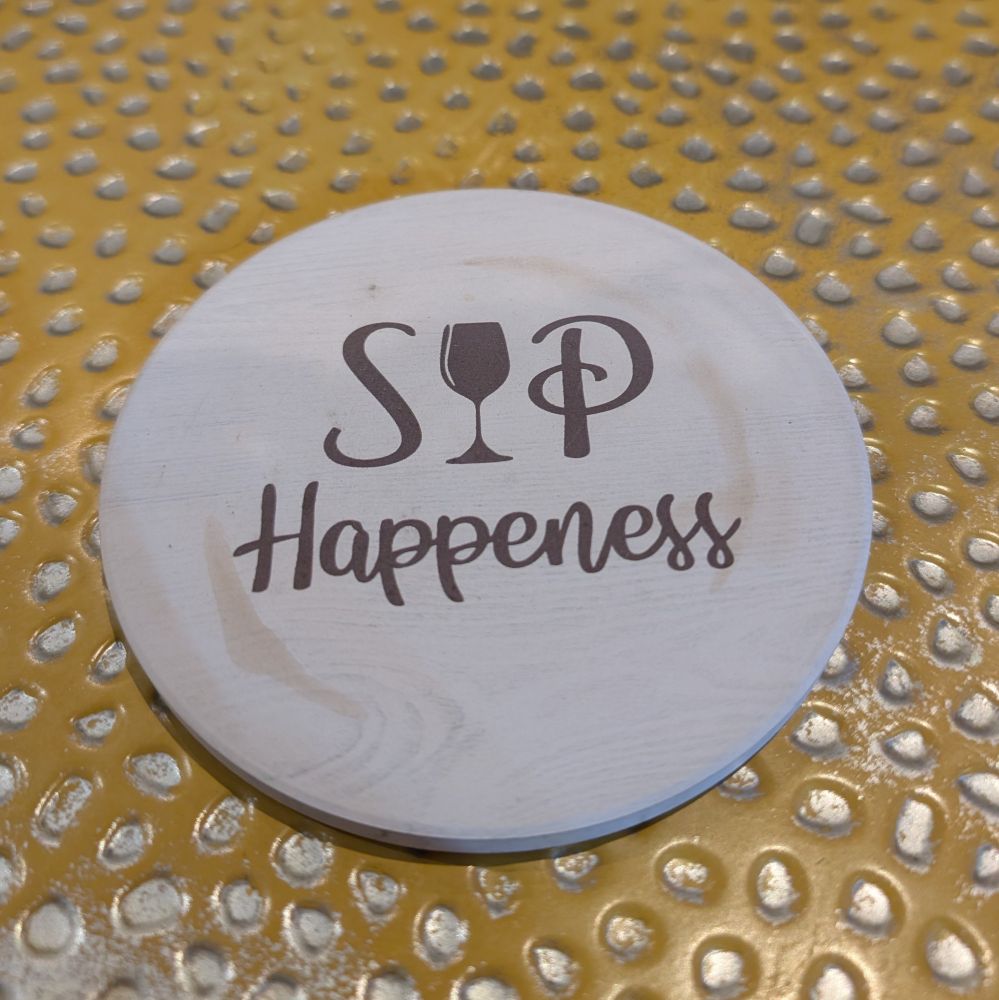 A coaster that is so close to being correct but instead says "SIP Happeness" a wine glass graphic replaces the 'i' in 'sip'. 