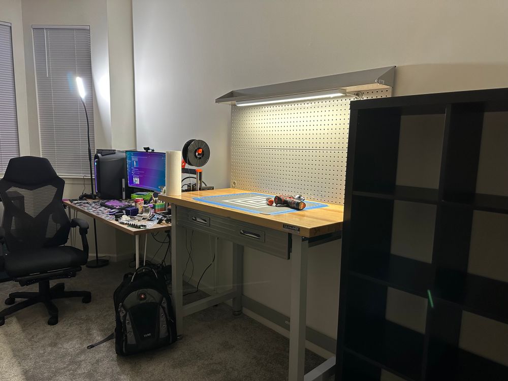 Computer desk, workbench, and shelf along wall