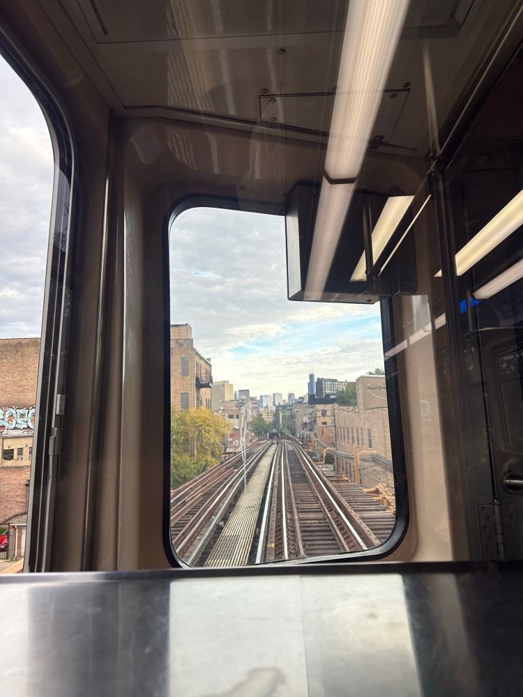 Blue Line into Chicago. Tracks in front of train lined with buildings and a horizon of Chicago’s skyscrapers. 