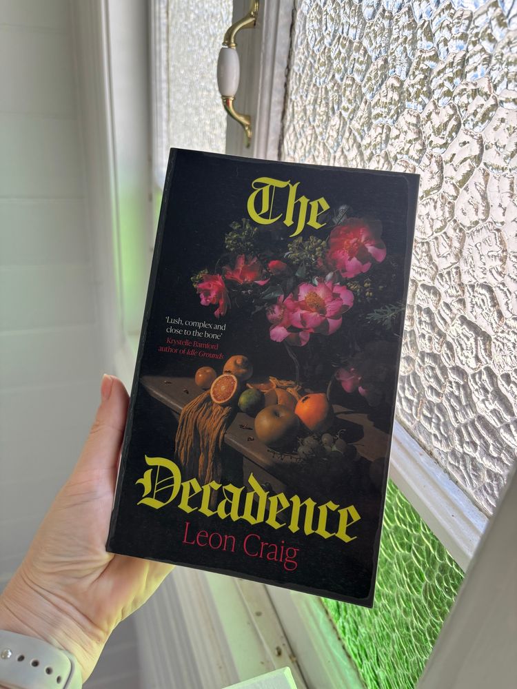 Holding a book against old casement windows: The Decadence by Leon Craig