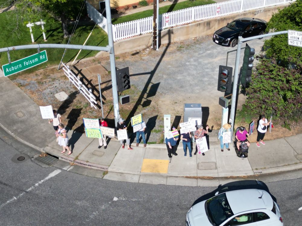Drone photo of about 20 protesters on a street corner in Auburn CA