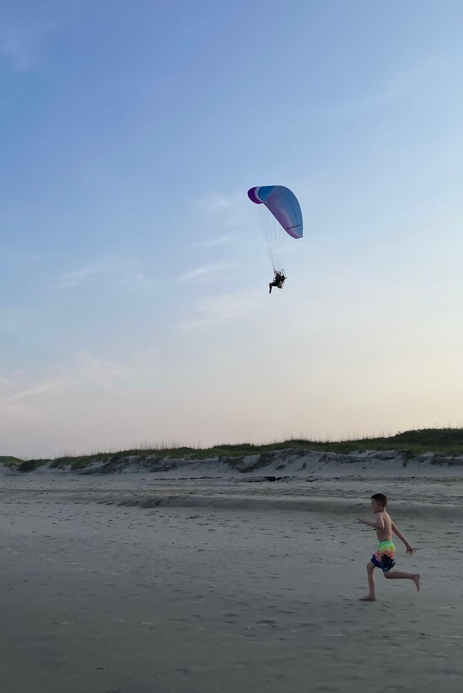 Paraglider over the beach during sunset 