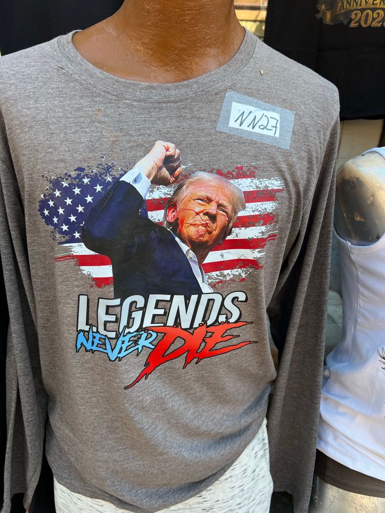 T-Shirt wieder mit Trump nach dem Attentat mit Faust und Flagge, Text: LEGENTS NEVER DIE (DIS sieht aus wie mit Blut geschrieben)