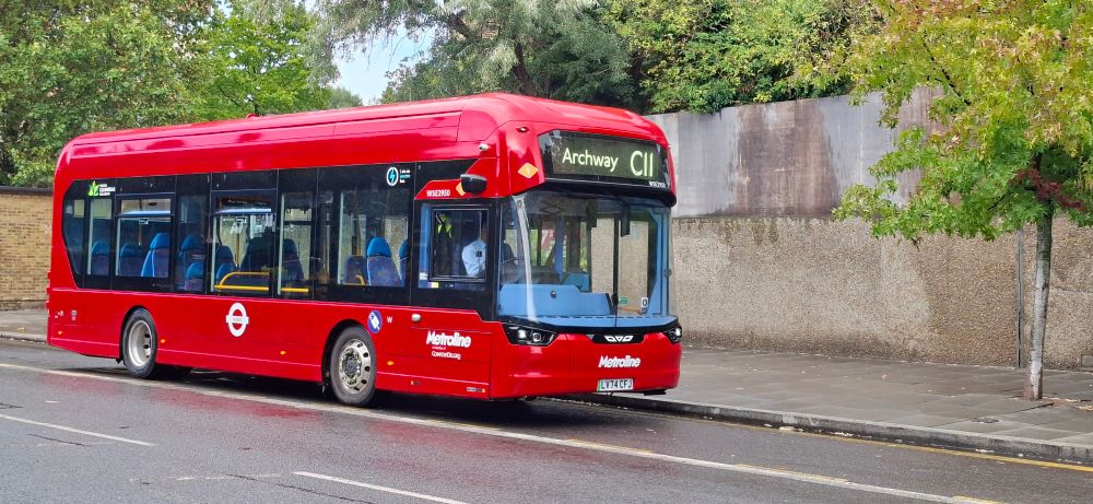 A red single decker bus at a bus stop.