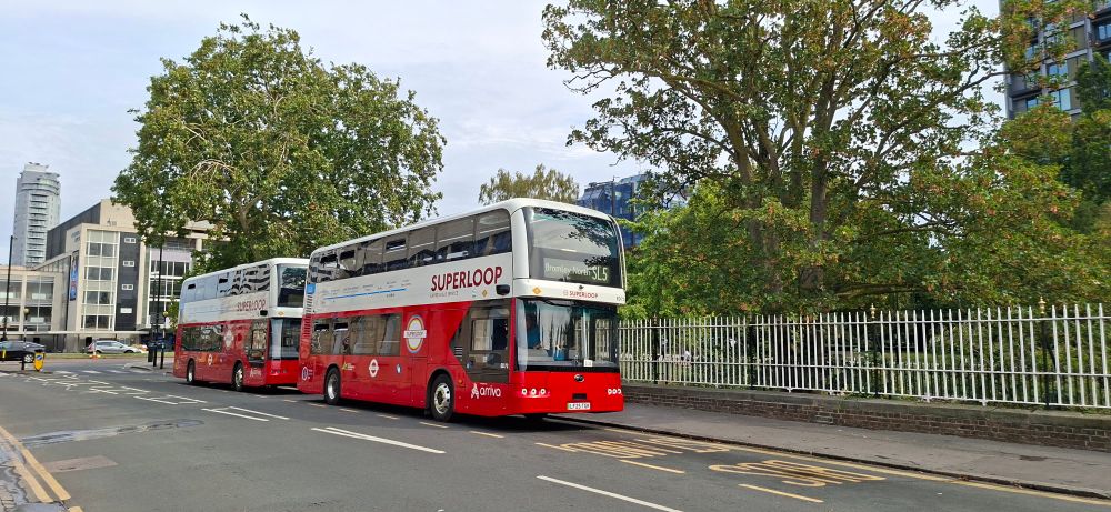 Two double decker buses in Superloop livery with red and white at the bus stand.