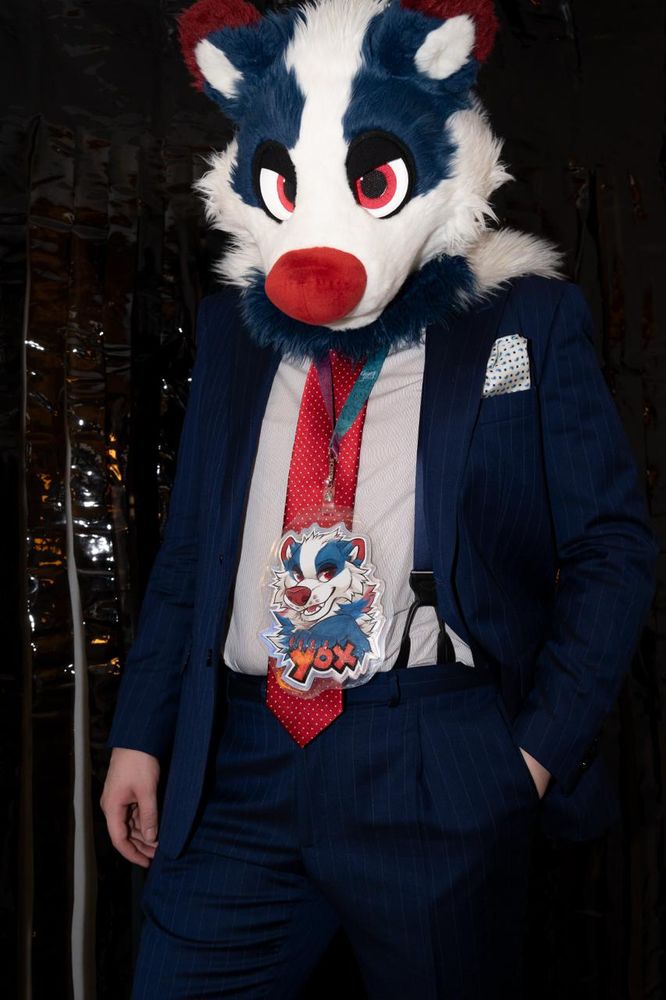 Badger fursuiter in navy blue pinstripe business suit and red tie