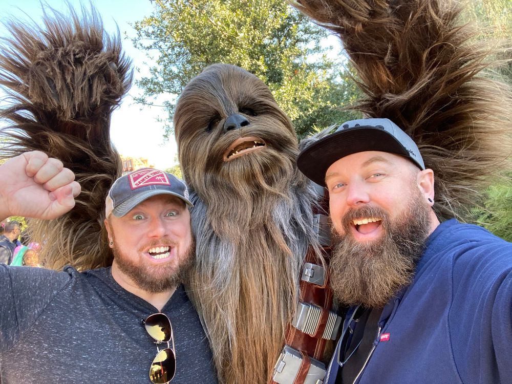 Two guys getting their photo taken with Chewbacca. 
