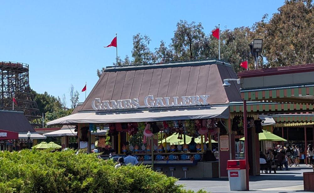A place for carnival games called "Games Galery" outside. Several red flags on the roof.