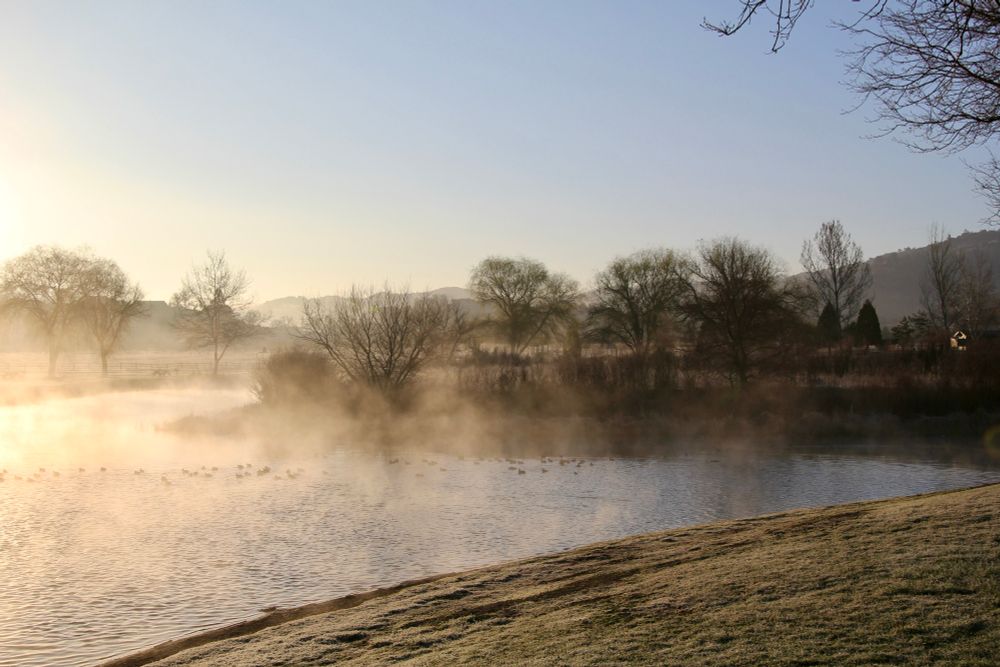 Early morning shot of the lake. Thin layer of fog arising from the lake surface creating a mystic atmosphere. 