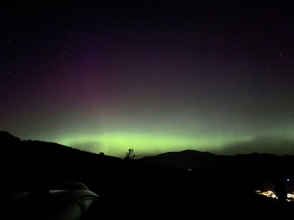 Crappy phone photo of green auroral glow on the horizon.