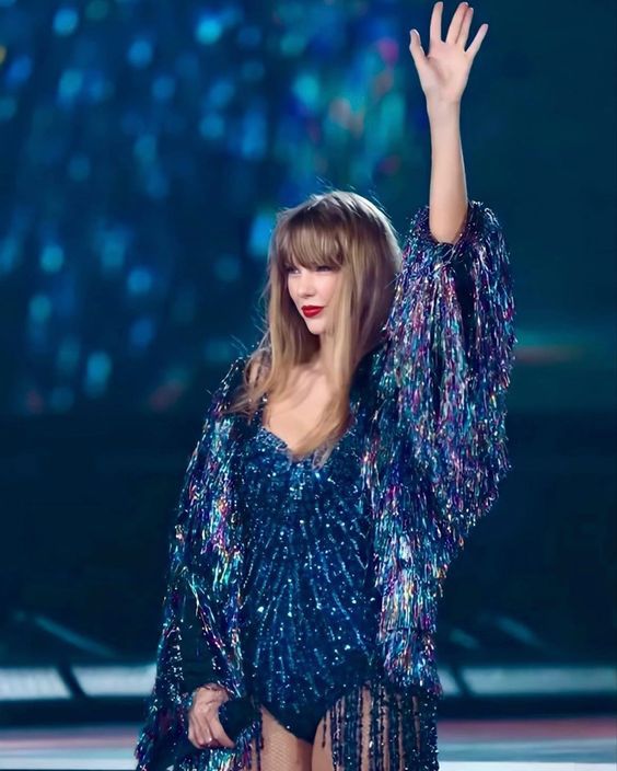 Taylor swift sinks into the floor after her midnights era. She is wearing the original navy bodysuit and the multicolored tinsel jacket
