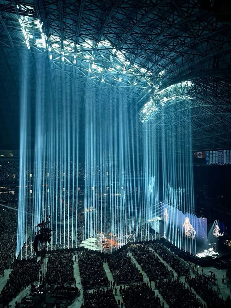 Taylor Swifts Eras Tour Stage lit up with lights going vertically to the ceiling
