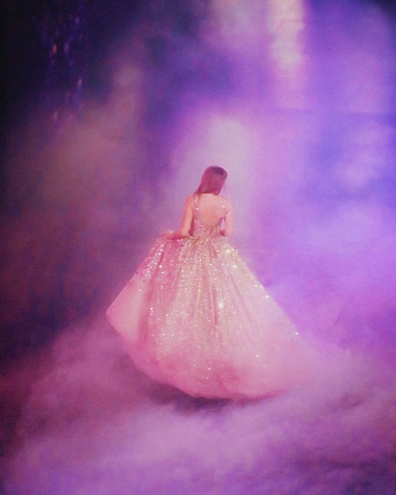 Taylor swift in her champagne speak now dress, surrounded by fog clouds reflecting pink and purple light 