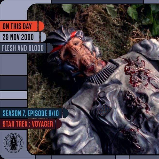 A severely injured alien lies on the ground in a wooded area, wearing a metallic gray armored suit that is torn open and covered in blood. The alien’s face is ridged and reptilian with deep-set features, and the chest area shows significant damage. The LCARS-themed sidebar reads: “On This Day — 29 Nov 2000 — Flesh and Blood,” with “Season 7, Episode 9/10 — Star Trek: Voyager” below. The CloneStar Podcast logo appears in the lower-left corner.