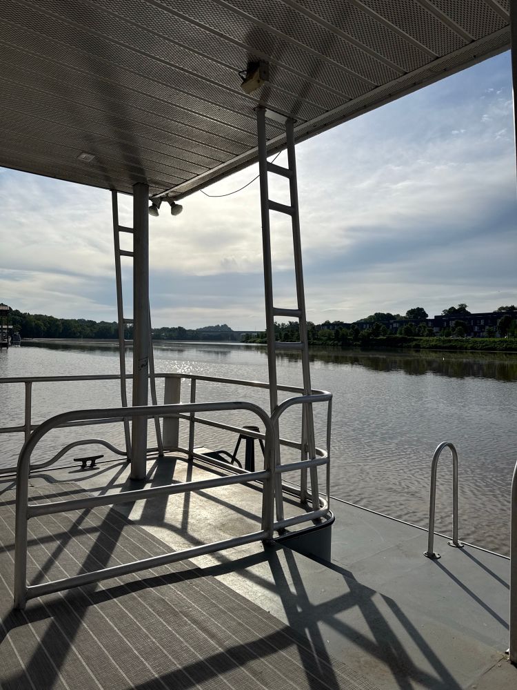 The view of the Tennessee river from the back deck of a houseboat. The water is a little murky. The sky is cloudy. But it’s a beautiful morning. 