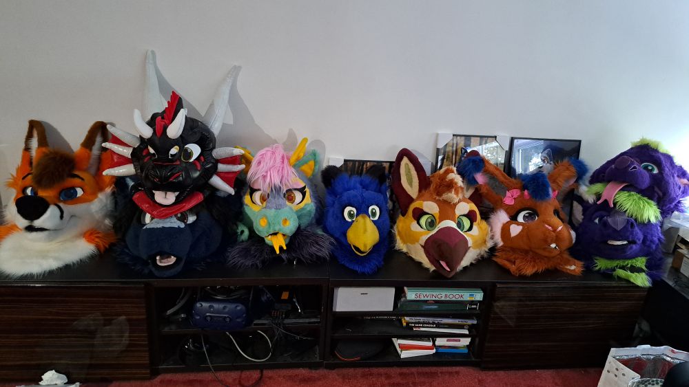 Several fursuit heads in a row on top of my AV cabinets
