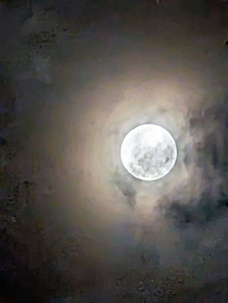 Moody picture of a full moon surrounded by clouds 