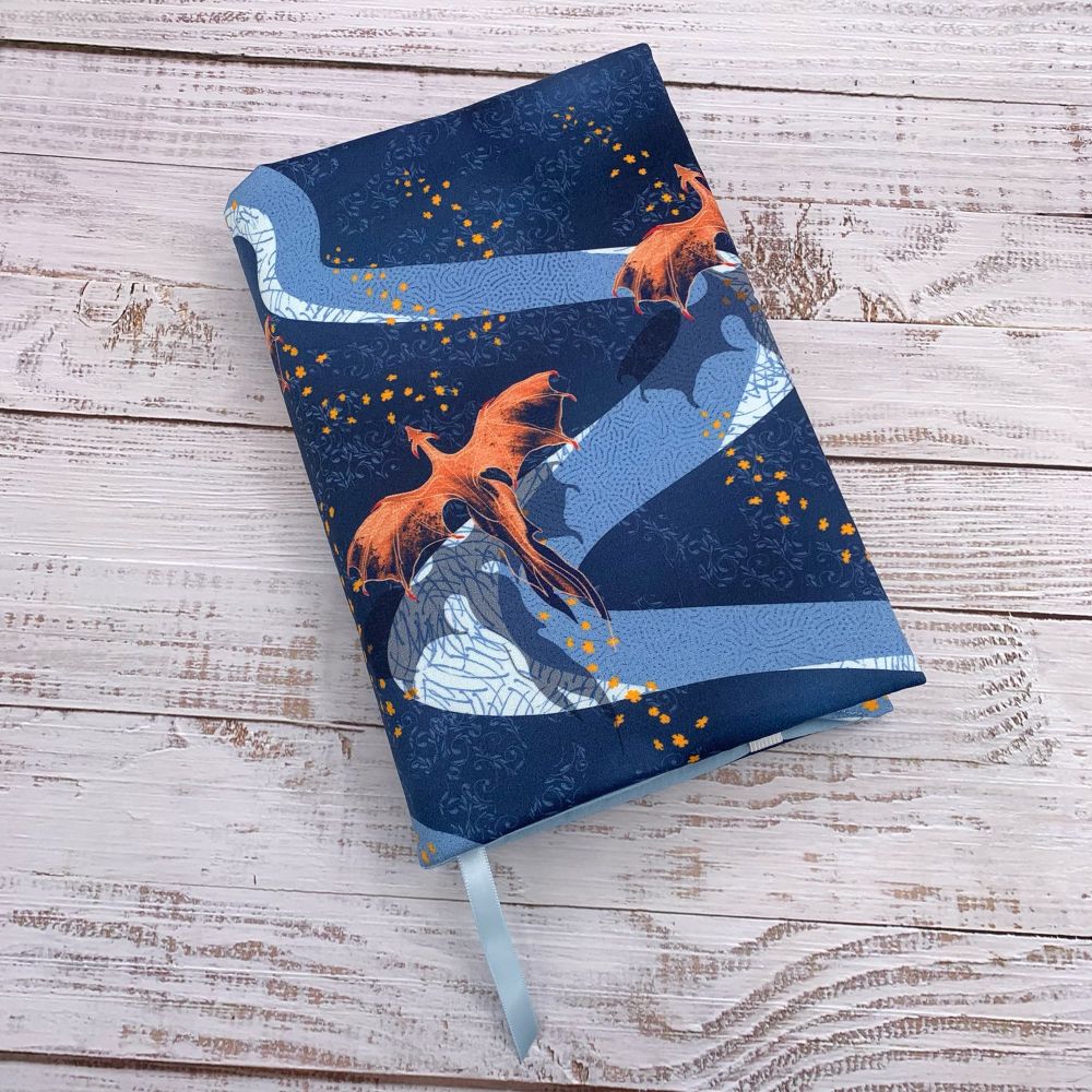 A fabric dust jacket with a beautiful reddish orange dragon flying over a blue background.