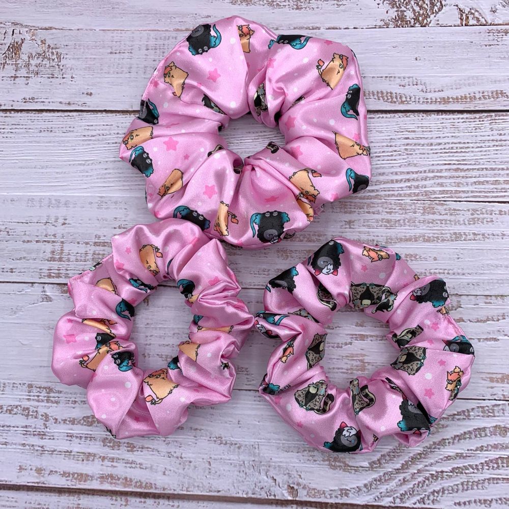 3 scrunchies displayed that have a custom print with Fly, Puck & Rikkus fursona scattered about on a pink background with darker pink stars and white and pink dots. The pattern is repeating. The scrunchie on top is thicker/shows more of the print than the bottom two.
Art by Crisuarts 