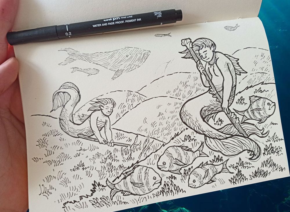sketchbook page photo with the drawing of a submarine landscape with rolling hills of seagrass being used to shepherd fat fishes. Two mermaids tend to it as some whale silhouettes can be seen in the distance.
