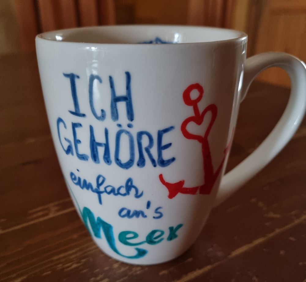 Weiße Tasse mit Text:
"Ich gehöre einfach ans Meer."