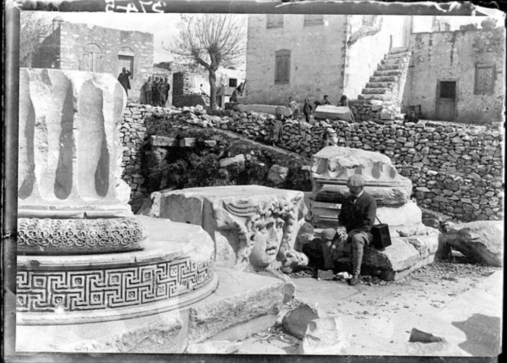 Hogarth sits  on base stone near capstone and pillar elements in Didim Turkey Apollo's temple 