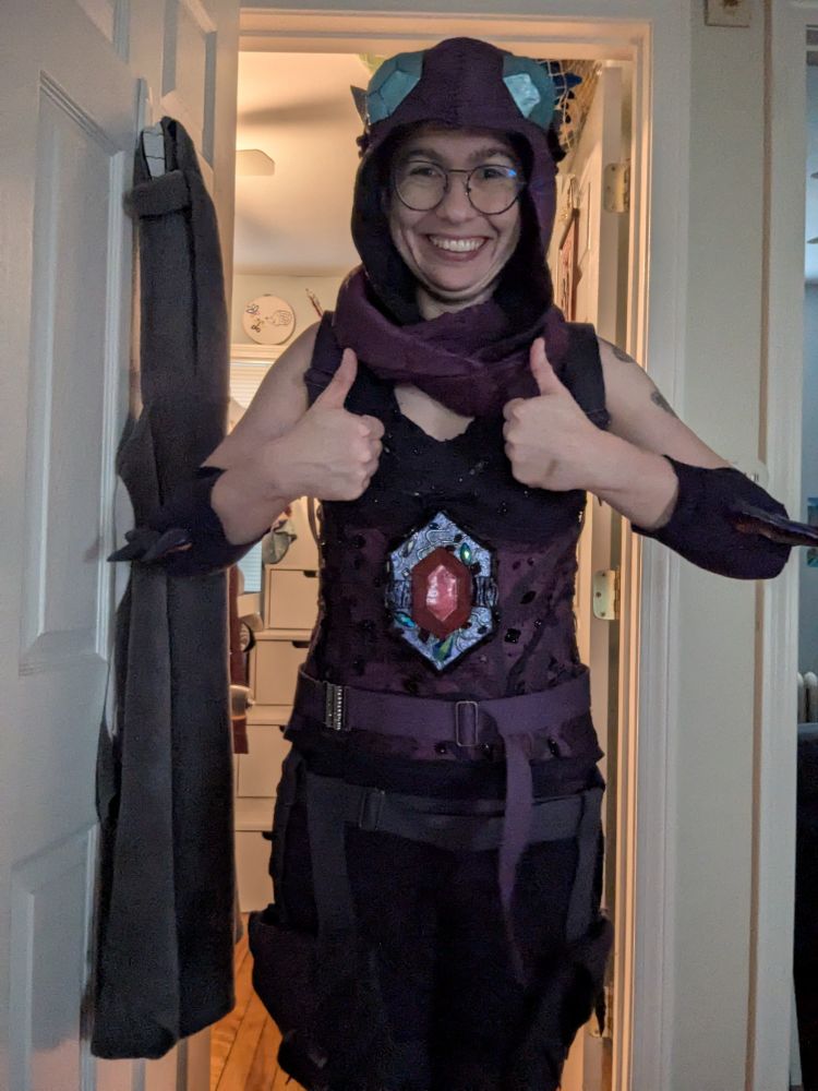 A person in a cosplay representing Sableye from Pokemon gives two enthusiastic thumbs up at the camera 