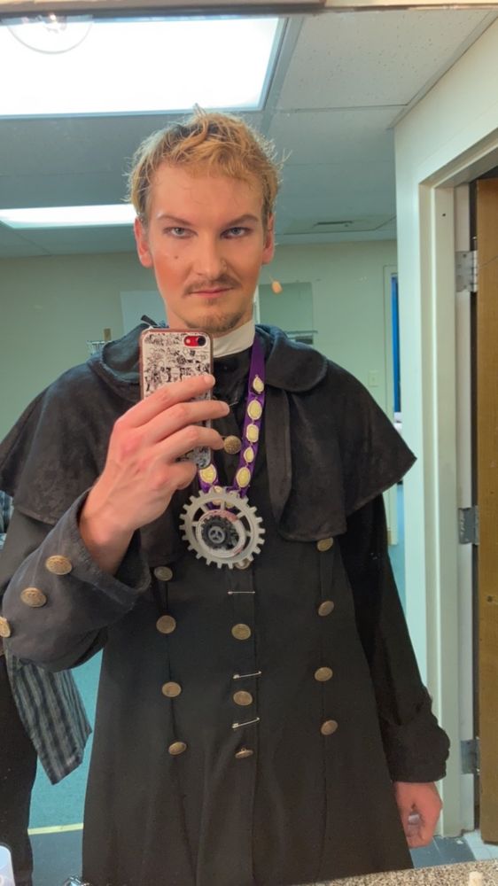 I am standing in front of a mirror dressed as my character, John Jasper, for a musical. He is dressed in Victorian steampunk attire and vaudevillian makeup.