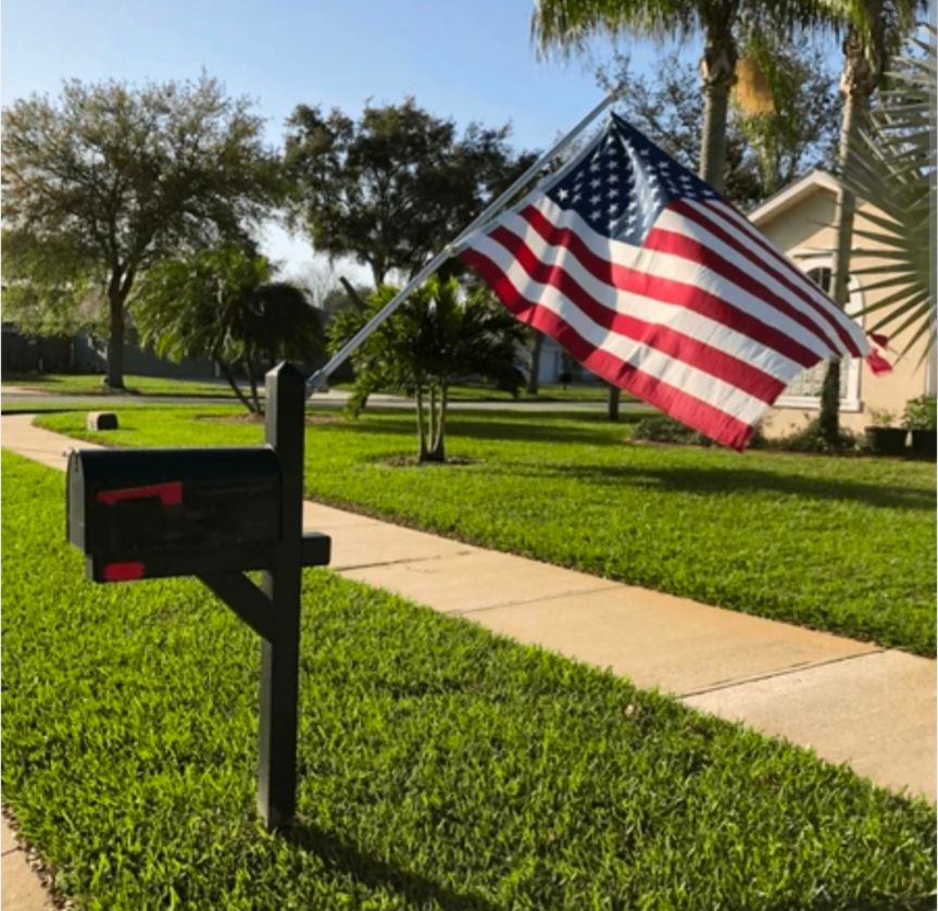 An american flag mounted on the back of a mailbox. It looks out of proportion and backwards and ridiculous 