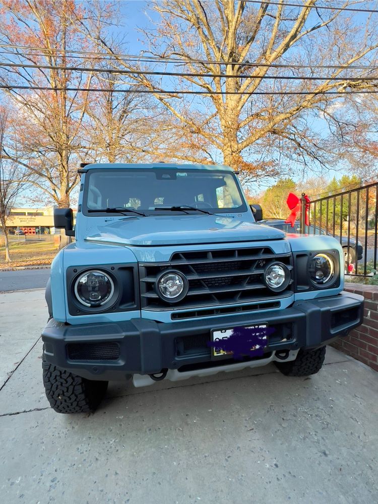 The front of a blue SUV with black grille on a concrete driveway. 