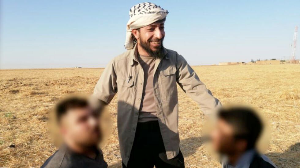 Abou Hatim Shaqra, Ahrar al-Sharqiya leader, center; two victims faces are blurred. The photo was taken right before their executions.