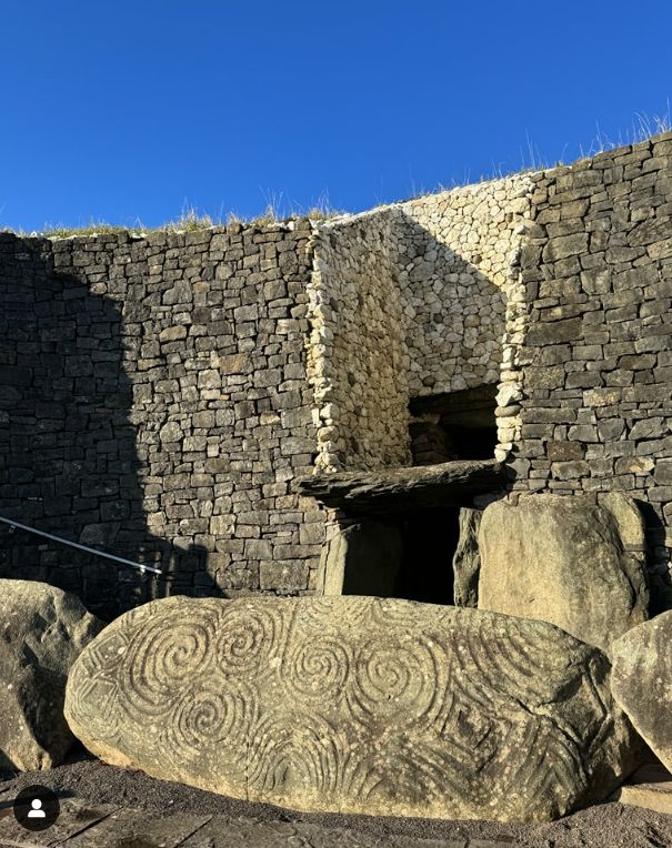 Photo of the entrance to the megalithic passge tomb at Bru an Boinne, Newgrange, Co Meath, Ireland. The large entrance stone is decorated in craved large and small swirls.