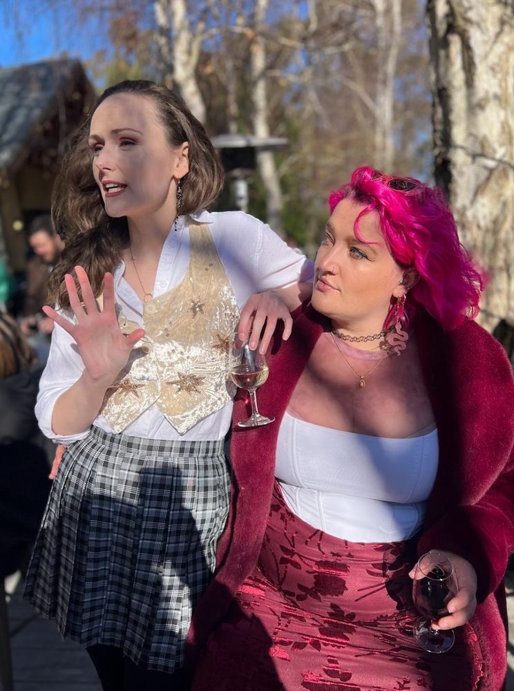 Dael and a friend looking well put together and like they're engaged in sophisticated conversation while holding glasses of wine