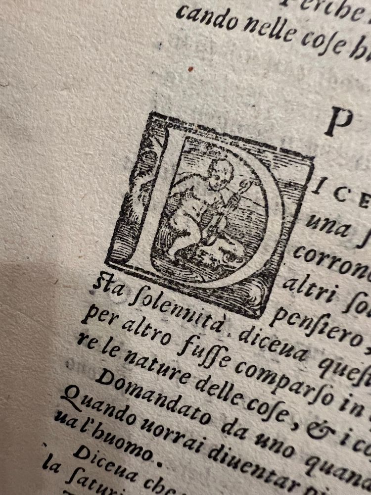 Engraved initial “D” from an early printed book, featuring a putto seated on a dolphin, holding a violin in left hand.