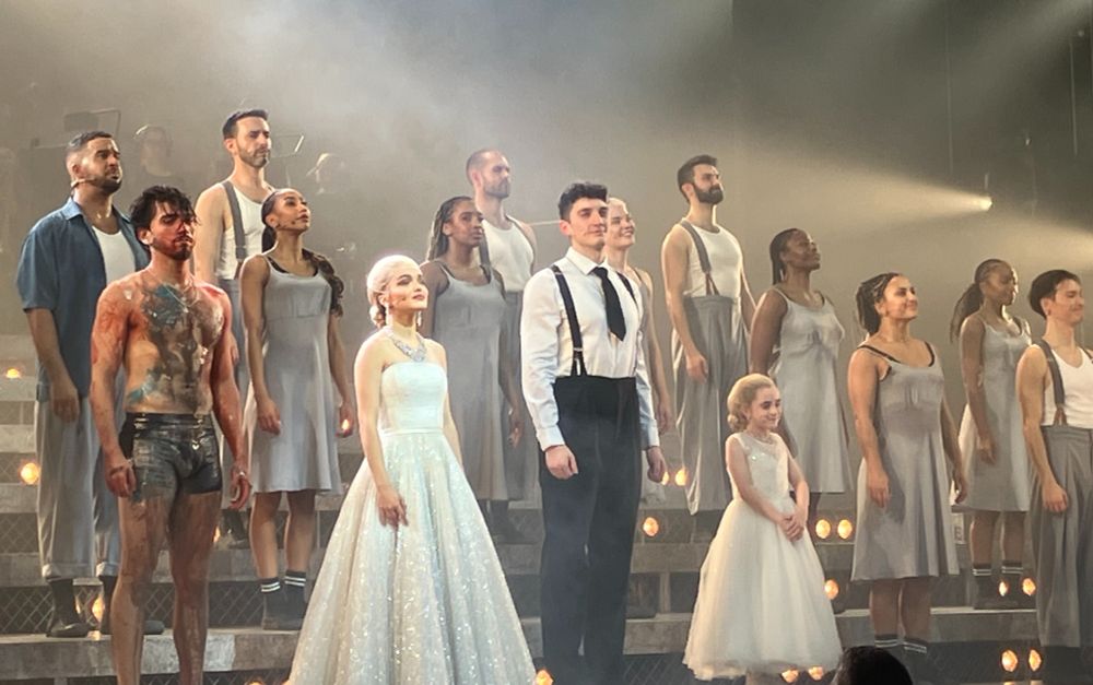 Rachel Zegler, in a shimmering white gown and diamonds, takes her bow as Evita with the rest of the cast, including Diego Andres Rodriguez as Che and James Olivas as Perón.

