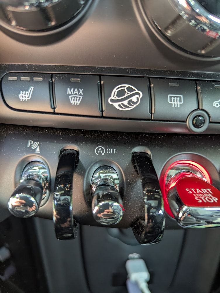 A car console with various buttons (seat heater, defrost, etc.). One of which is now labeled with a turtle shell.