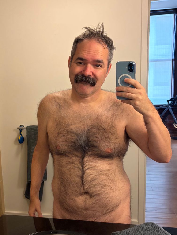 Furry man with mustache taking a dirty mirror selfie
