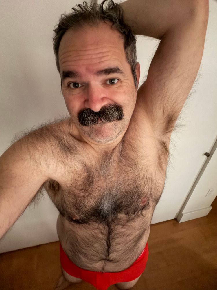 Furry man with mustache wearing orange underwear 