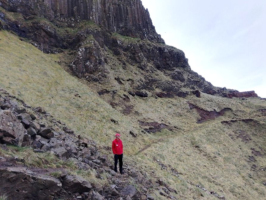 Image of active scree at The Amphitheatre, Causeway coast.
Man in red jacket and hat standing part way up scree slope for scale.