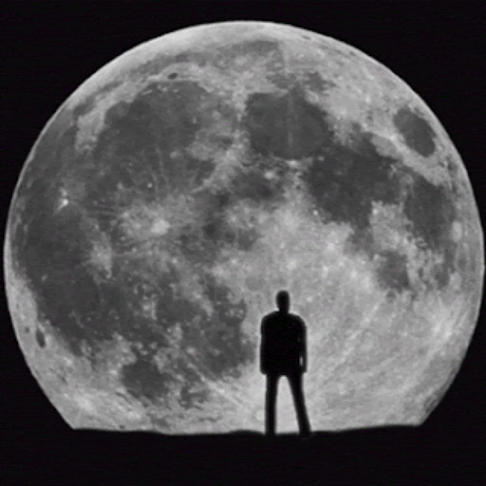 a man stands in front of a full moon in a black and white photo