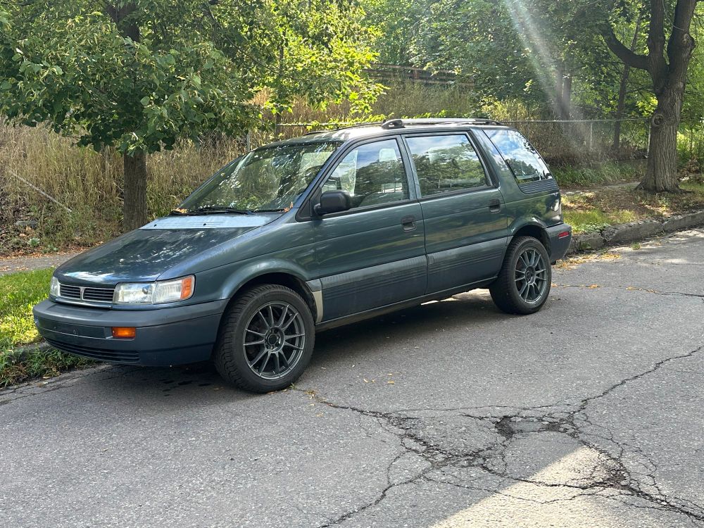 A scruffy, green Eagle Summit on aftermarket rims.