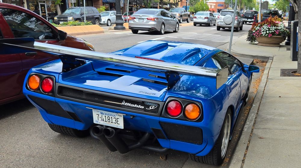 A blue Lamborghini Diablo SV parked on a busy street.