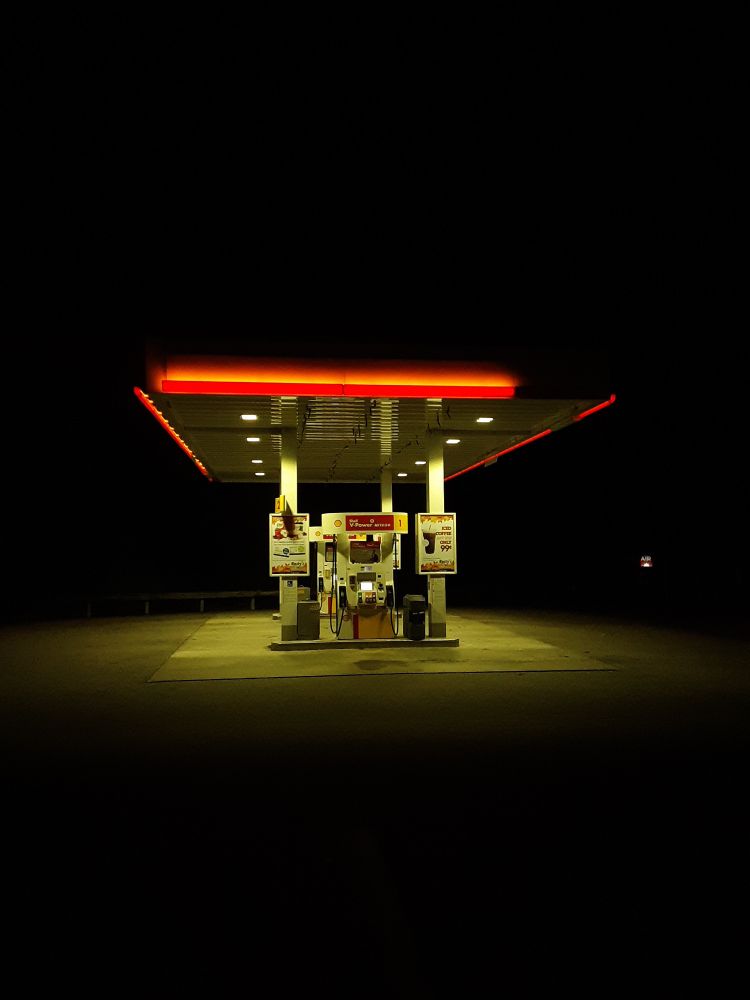 a late night shot of a gas station pump, with the yellow and orange neon lights particularly strong