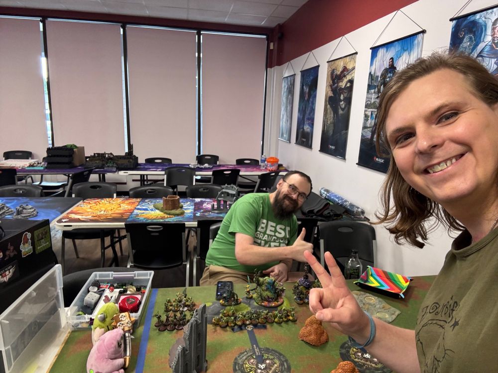 Two new friends smiling before a Warhammer game. 