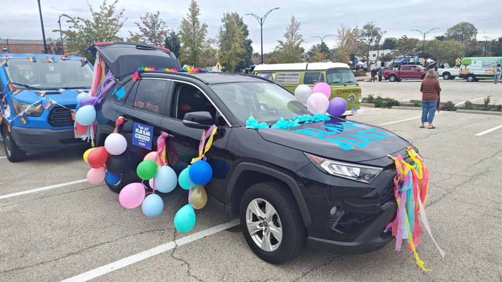 A black SUV decorated with rainbow streamers and balloons for Dylan Blaha with Blaha Blast written in blue on the hood of the car.
